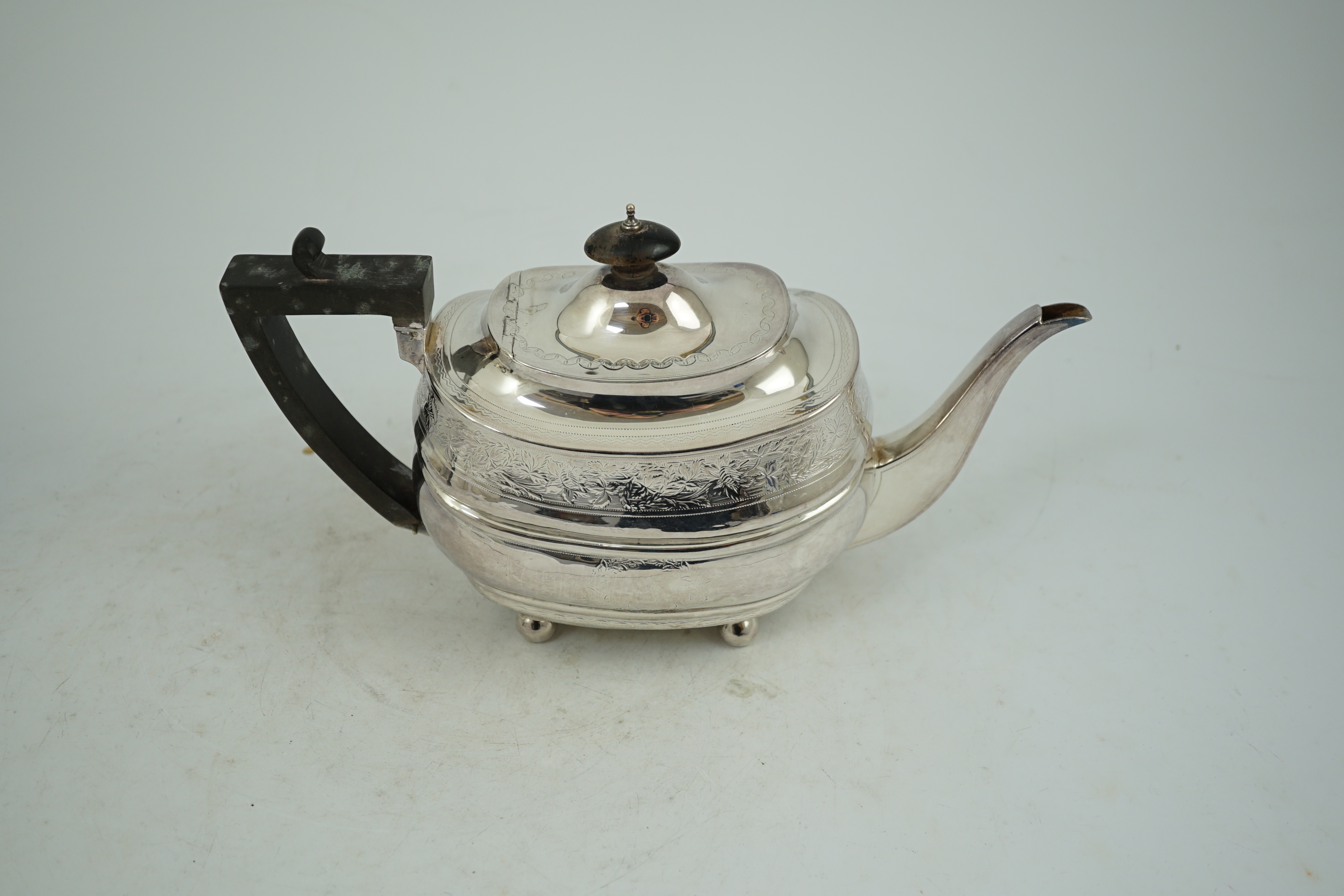 A George III engraved silver shaped oval teapot, on ball feet, Thomas Wallis II, London, 1807, gross weight 16.1oz.